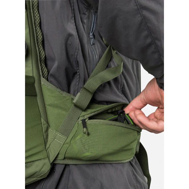 Close-up of a person wearing an olive green hydration backpack over a dark gray jacket, demonstrating a side pocket with a zipper.